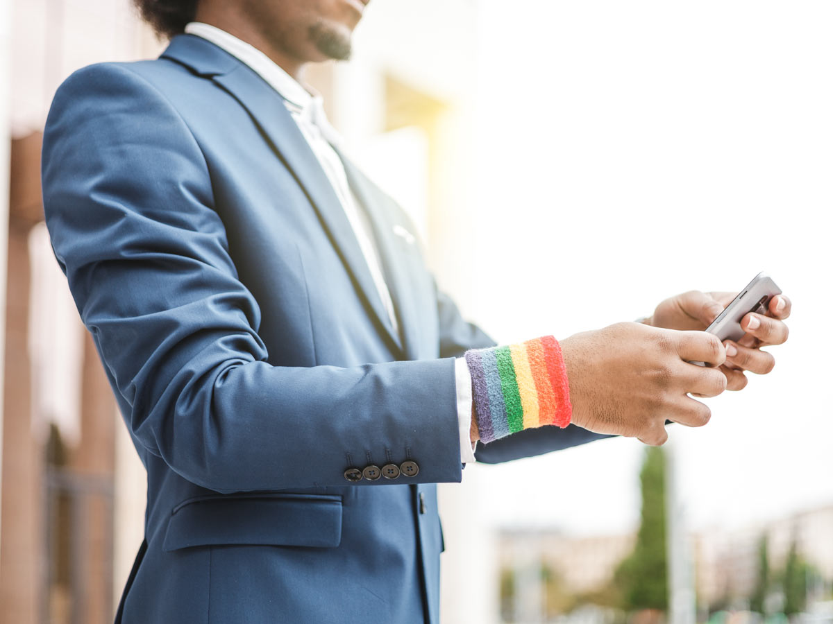 Un employé d'entreprise portant un bracelet Pride utilise son smartphone à l'extérieur 