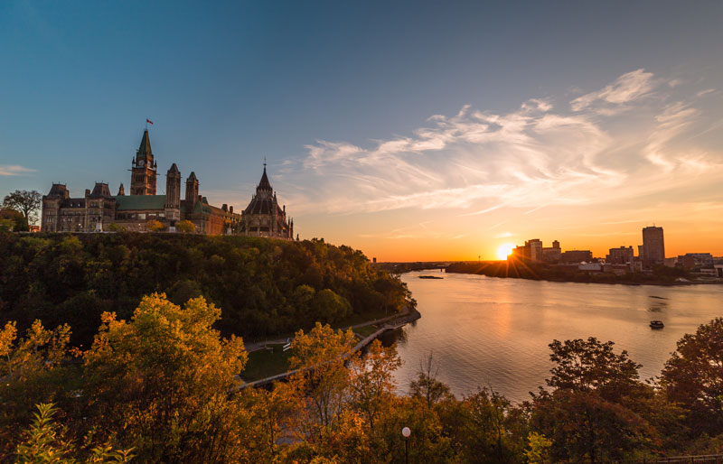 Ottawa Parliament buildings and river at sunset.